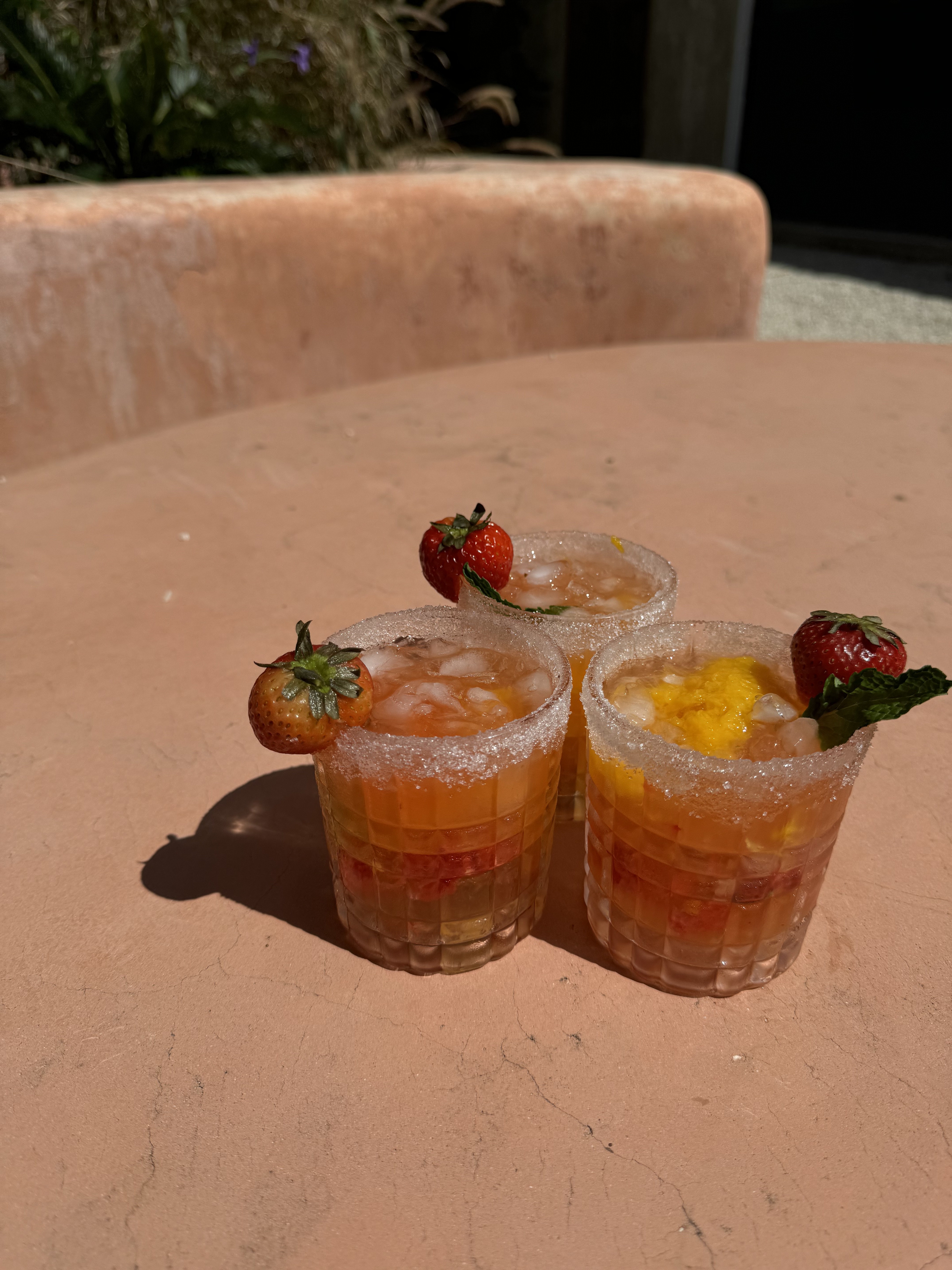 Three vibrant mocktails garnished with fresh fruit